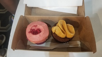 a photo of Two cup cakes sitting side by side inside a takeway cardboard box