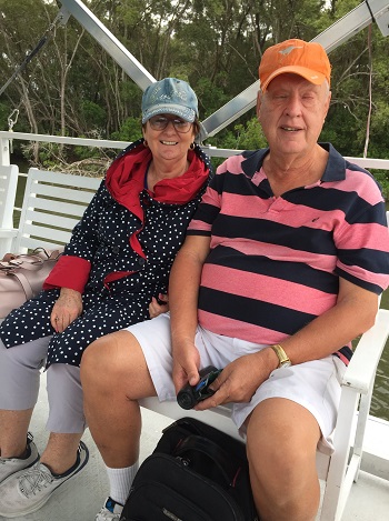 a photo of Elizabeth and Peter sitting side by side on the boat smiling at camera