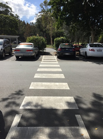 a photo of a long white zebra crossing straight ahead traversing a carpark 2