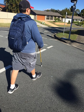 photo of a Man crossing light controlled crossing with long cane
